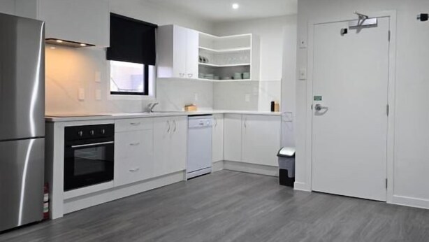 A modern kitchen with white cabinetry, a stainless steel refrigerator, and a built-in oven. - Microtel Lodge (Hamilton)