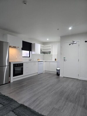 A modern kitchen with white cabinetry, a stainless steel refrigerator, and a built-in oven.