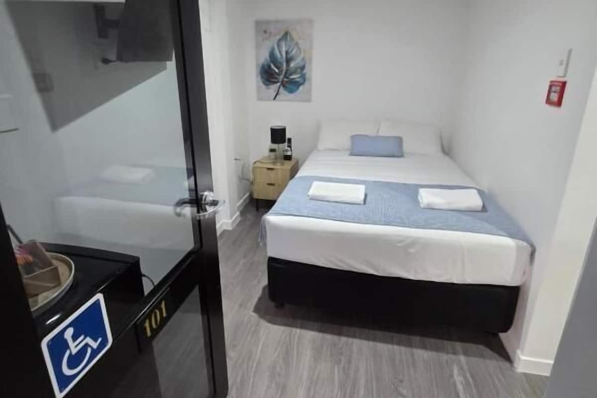 A hotel room with a bed, a nightstand, a painting, and a wheelchair-accessible area.