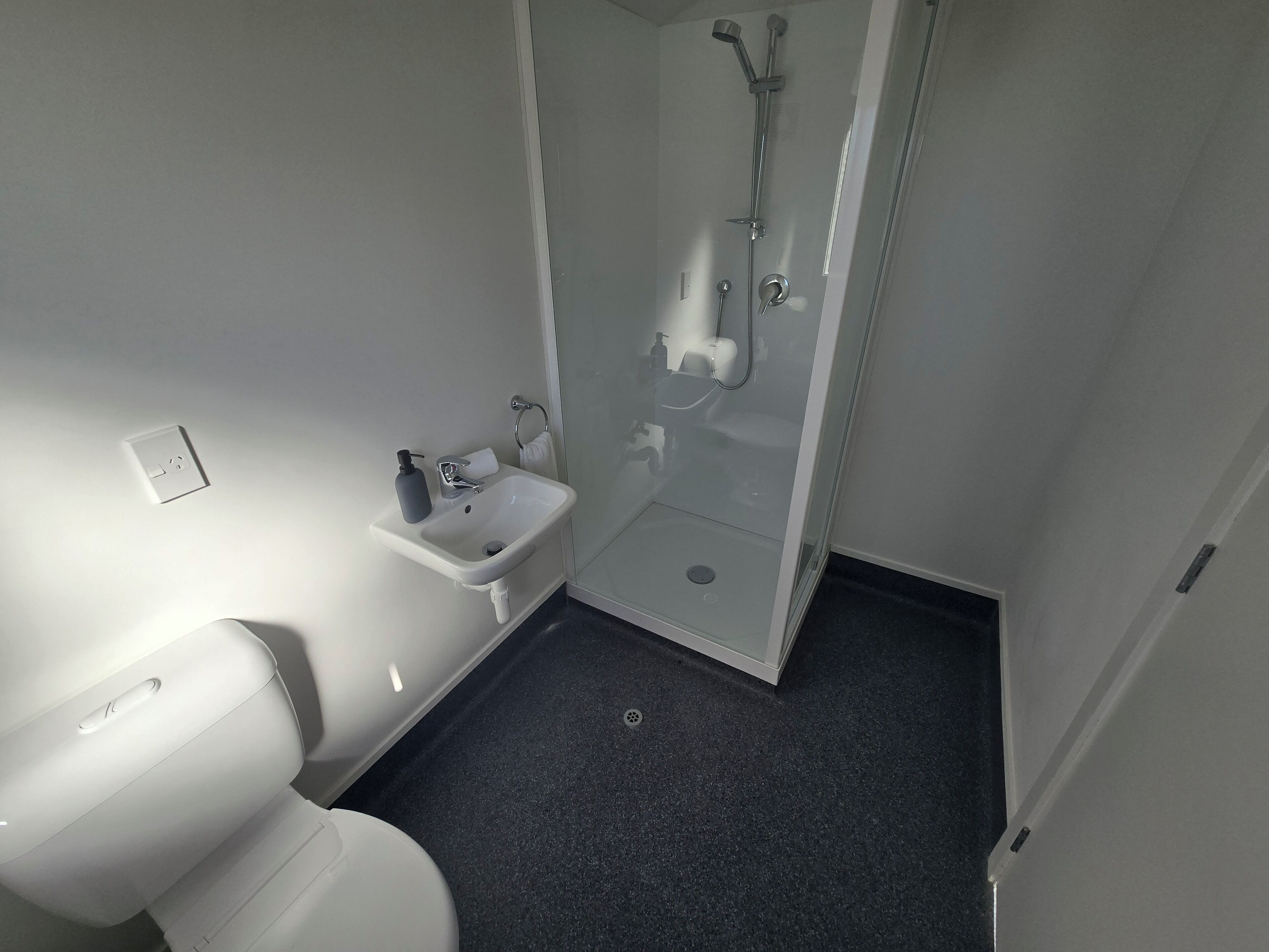A small, modern bathroom with a toilet, sink, and glass-enclosed shower.