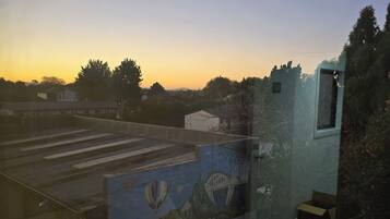 Una habitación con un amplio ventanal que da a un estacionamiento y un mural en la pared.