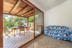 Un patio couvert avec une table et des chaises, un canapé et une vue sur la verdure environnante.