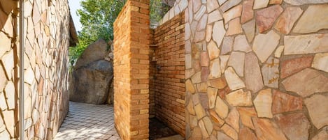 A stone-walled outdoor area with a brick structure, possibly a sauna or hot tub, surrounded by a paved floor.