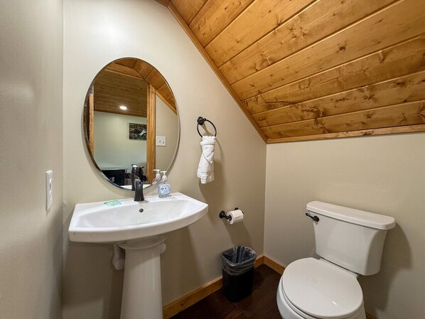 Un baño pequeño con techo de madera, un lavabo blanco, un inodoro y un espejo.