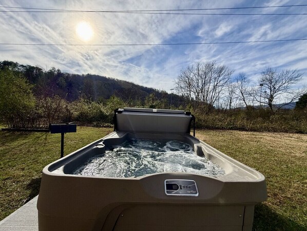 Un jacuzzi con panel de control, rodeado de césped y árboles.