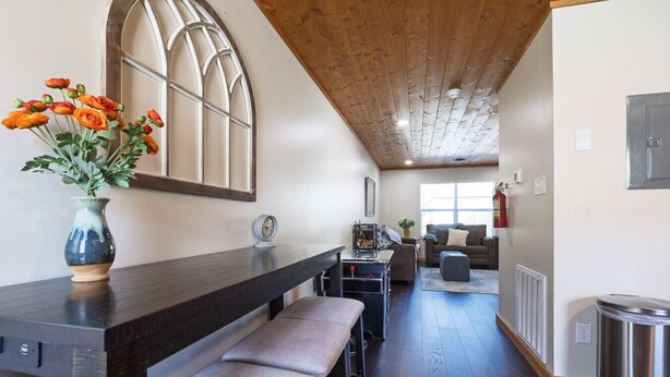 Een moderne keuken met donkere aanrechtbladen, een houten plafond en een groot raam.