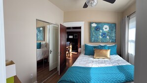 Ein Schlafzimmer mit einem Bett, einem Spiegel, einem Gemälde und einem Deckenventilator.