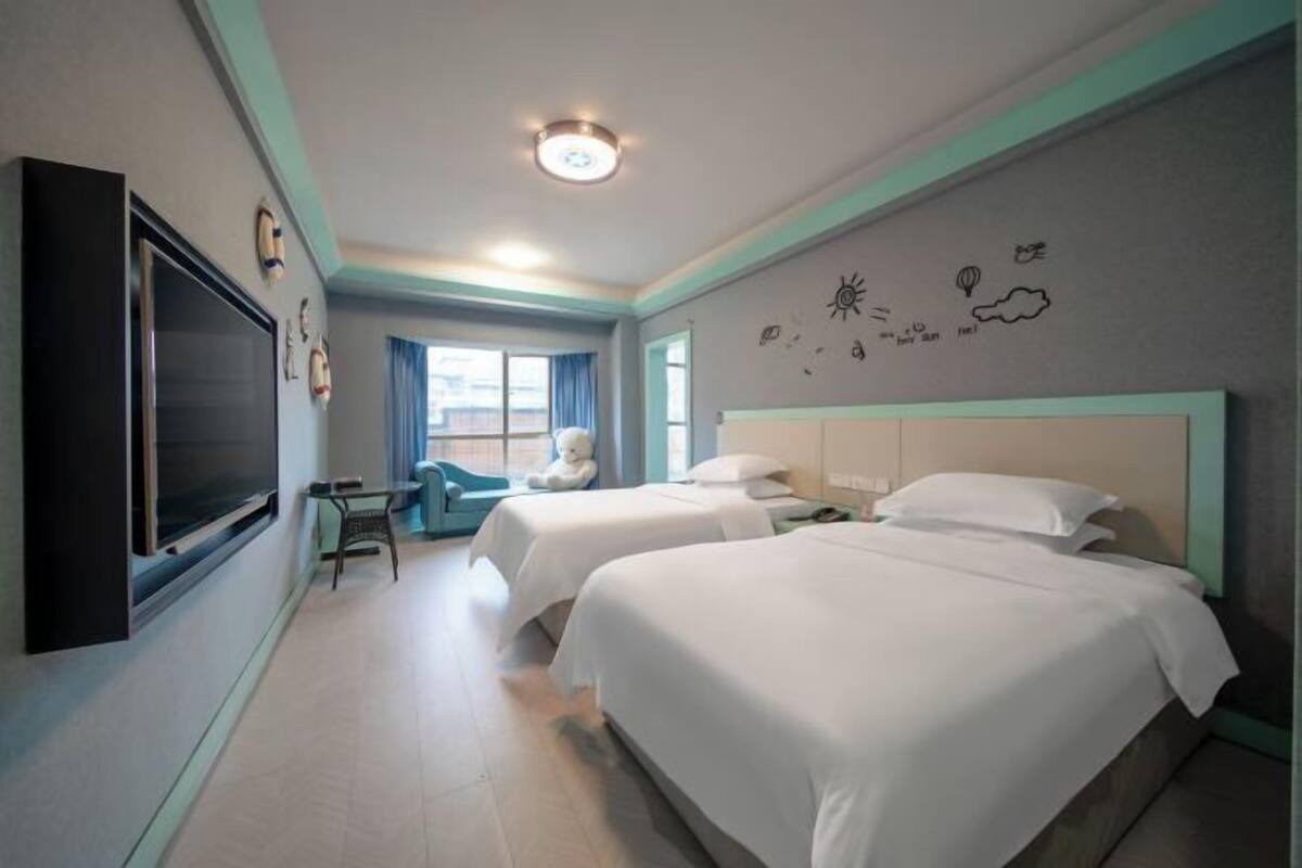 Ein Hotelzimmer mit zwei Betten, einem Fernseher, einem Schreibtisch und einem Fenster.