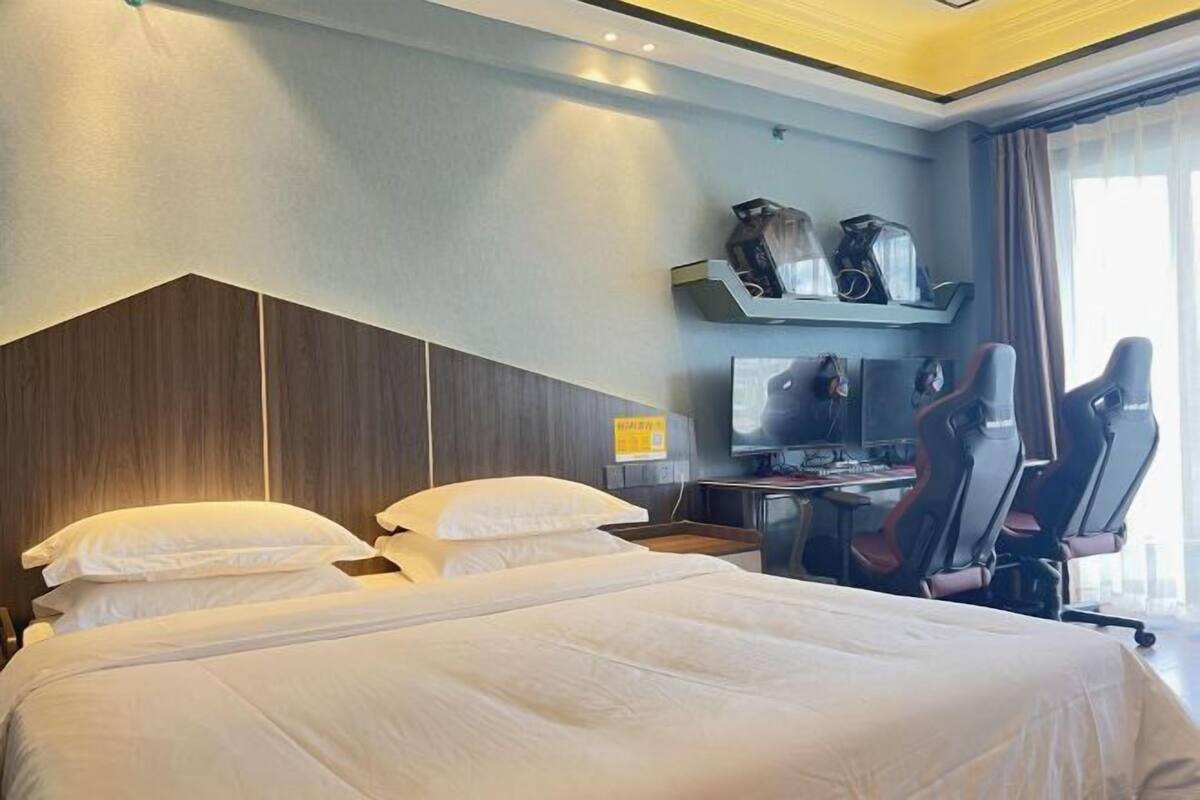Ein Hotelzimmer mit zwei Betten, einem Schreibtisch mit Computer und einem Fernseher.