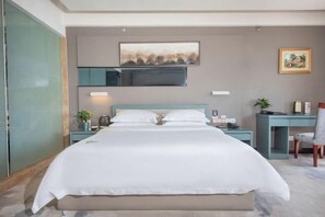 A modern hotel room with a large bed, a desk, a chair, and a small table with a plant. - Ganxian Tianyue International Hotel (Ganxian Qili Ancient Town Resort Branch) (Ganzhou)