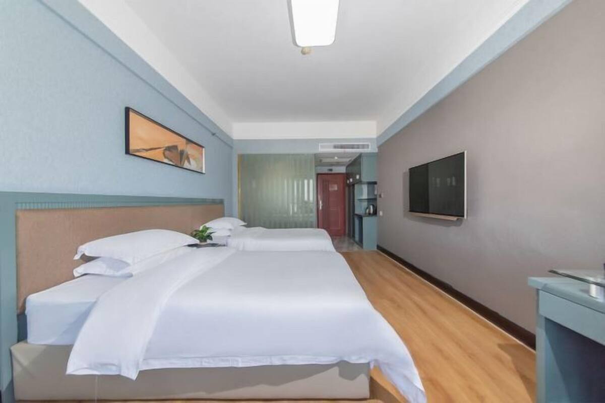 Ein Hotelzimmer mit einem großen Bett, einem Nachttisch, einem Flachbildfernseher und einer Tür zu einem Badezimmer.