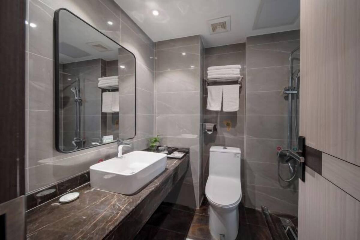 Ein modernes Badezimmer mit großem Spiegel, Waschbecken, Toilette und Duschbereich.