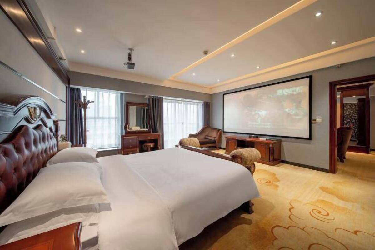 Ein Hotelzimmer mit einem großen Bett, einem Fernseher, einem Schreibtisch und einem Sofa.
