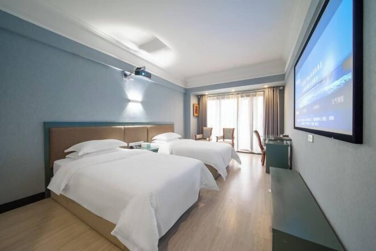 Ein Hotelzimmer mit zwei Betten, einem Fernseher und einem Schreibtisch.