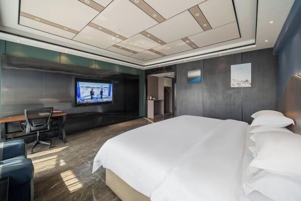 A modern hotel room with a large bed, a desk with a chair, a television mounted on the wall, and a framed picture on the wall. - Ganxian Tianyue International Hotel (Ganxian Qili Ancient Town Resort Branch) (Ganzhou)