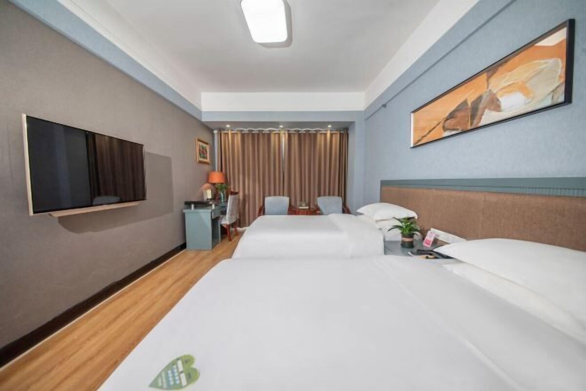 A hotel room with a large bed, a flat-screen TV, a desk with a lamp, and a painting on the wall.