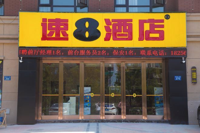 A hotel with a prominent yellow sign, large glass windows, and a visible entrance.