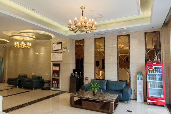 Un vestíbulo de hotel con una recepción, zona de estar y una máquina expendedora.