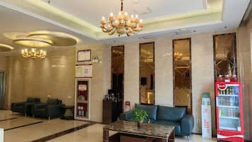 Un vestíbulo de hotel con una recepción, zona de estar y una máquina expendedora.