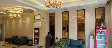 A hotel lobby with a reception desk, seating area, and a vending machine.