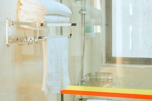 Ein Badezimmer mit Duschkabine aus Glas, einem Handtuchhalter mit gefalteten Handtüchern und einer Glastür zur Dusche.