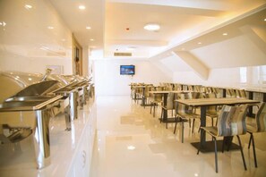 A modern dining area with a long counter and multiple tables, a television screen, and a polished floor. - Super 8 Hotel (Huaiyuan Yudu Avenue) (Huaiyuan)