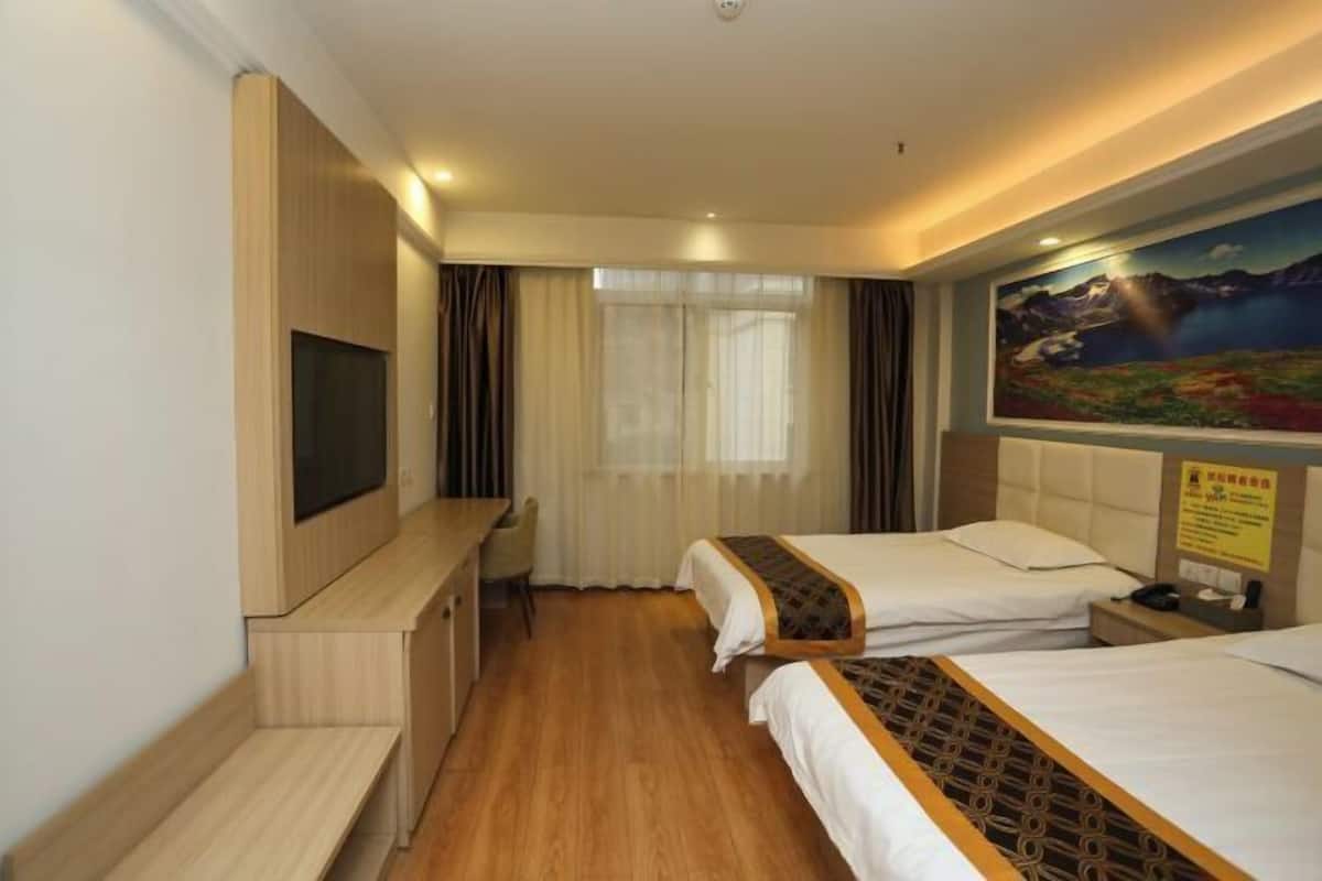 A hotel room with two beds, a desk, a TV, and a painting on the wall.