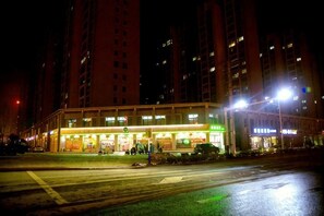 A multi-story building with illuminated signage, a crosswalk, and a wet street at night. - Super 8 Hotel (Huaiyuan Yudu Avenue) (Huaiyuan)