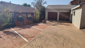 A paved driveway leading to a garage with a brick wall and a small garden area.