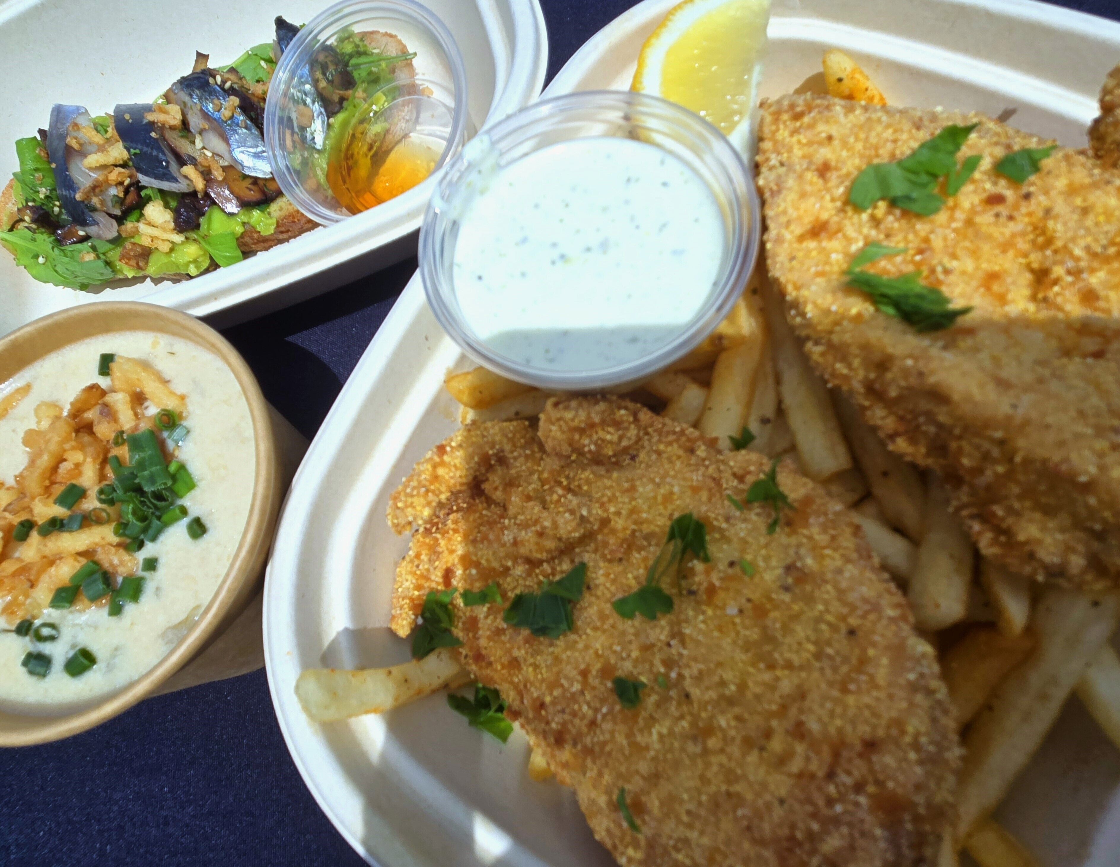 A plate with breaded fish fillets, fries, a salad, and two dipping sauces.