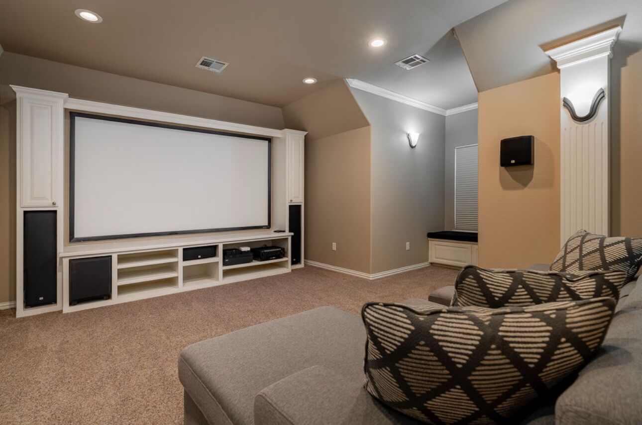 Une salle de cinéma privée équipée d’un grand écran, de sièges confortables et d’enceintes intégrées.