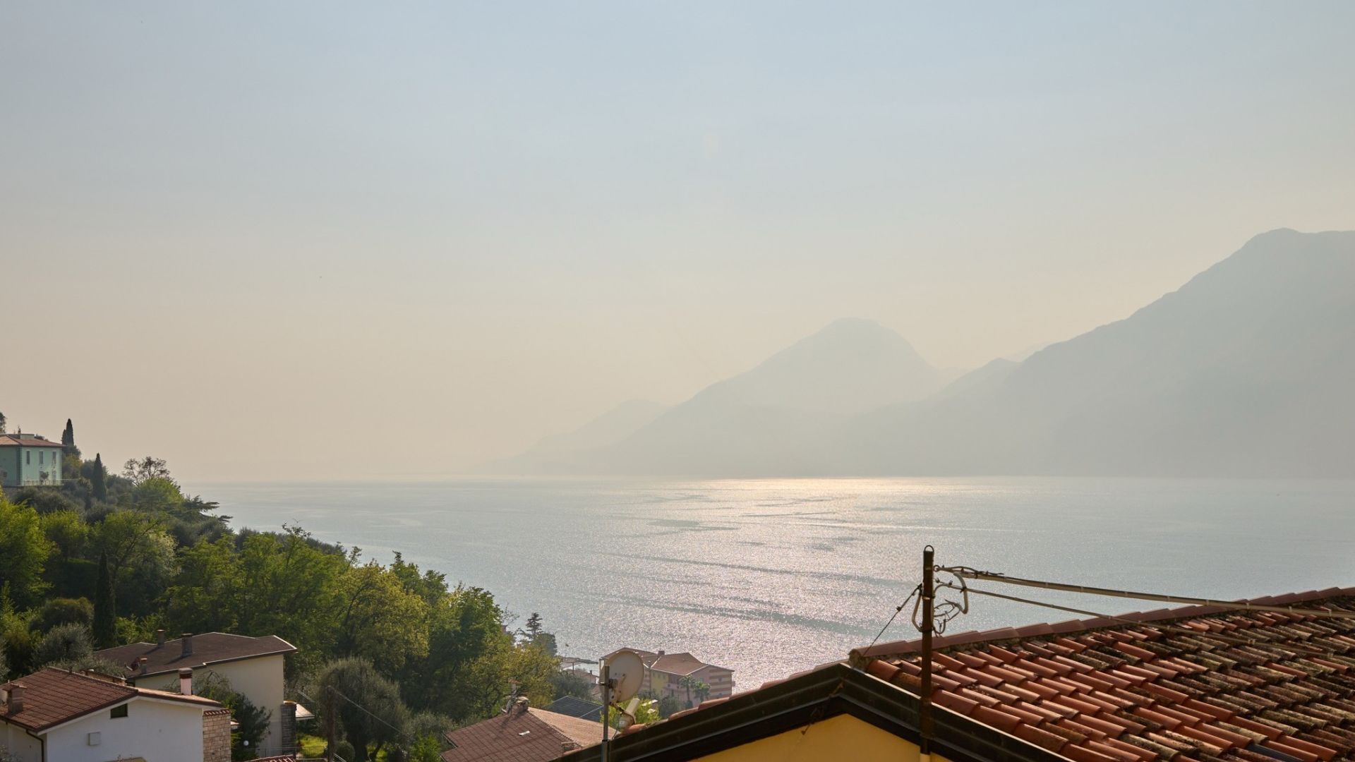 A coastal view with a mountain in the background, houses along the shore, and a clear sky.