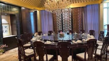 A conference room with a round table, chairs, and a chandelier.