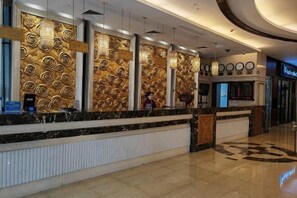 A hotel reception area with a marble counter, a decorative wall with circular patterns, and a digital display board. - Taoran Hotel (Beijing)