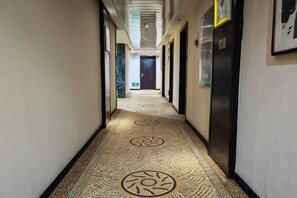 A hotel hallway with patterned carpet, doors, and a refrigerator. - Taoran Hotel (Beijing)