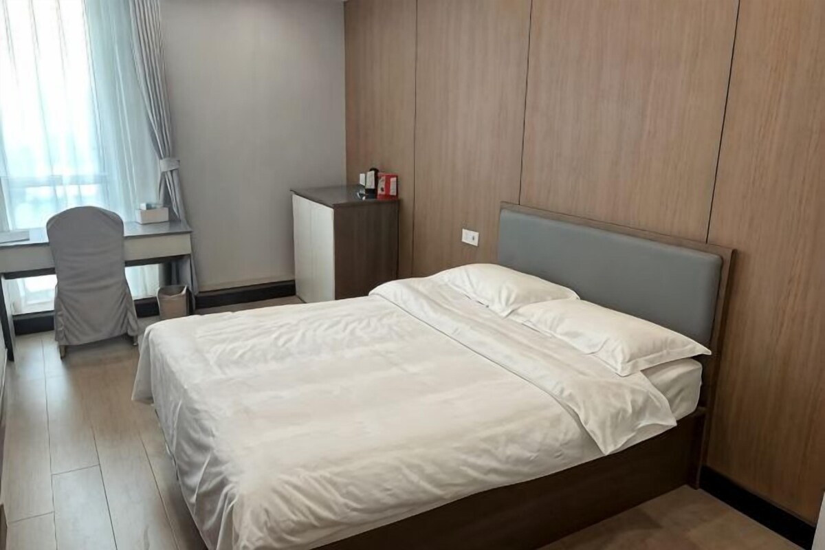A hotel room with a bed, desk, chair, and wardrobe.