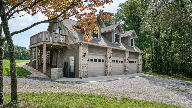 A two-story house with a covered porch, a garage with two doors, and a driveway. - Backwoods Bungalow (Crossville)
