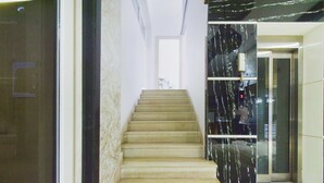 A staircase leading to an elevator in a building with marble walls. - Classic Devi Residency (Hyderabad)
