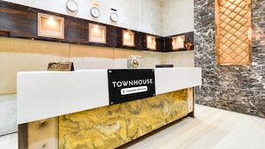 A reception desk with a sign reading 'TOWNHOUSE Company-Serviced,' a clock, and a wall clock above it. - Classic Devi Residency (Hyderabad)