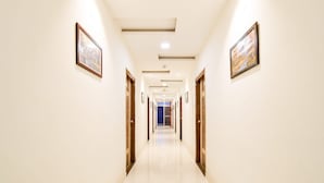 A hotel hallway with framed pictures on the walls, wooden doors, and a tiled floor. - Classic Devi Residency (Hyderabad)