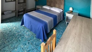 Une chambre à coucher comprenant un lit, une table en bois, une chaise, un luminaire suspendu et une armoire intégrée.