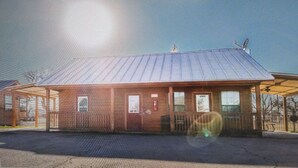 A single-story building with a metal roof, a covered porch, and a fenced area. - Cozy cabin with AC and WiFi in peaceful Sterling City.  Your small town adventure awaits! (Sterling City)