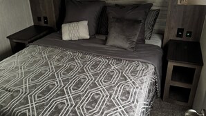 Une chambre à coucher avec un grand lit, des boiseries sombres et un téléviseur à écran plat fixé au-dessus du lit.