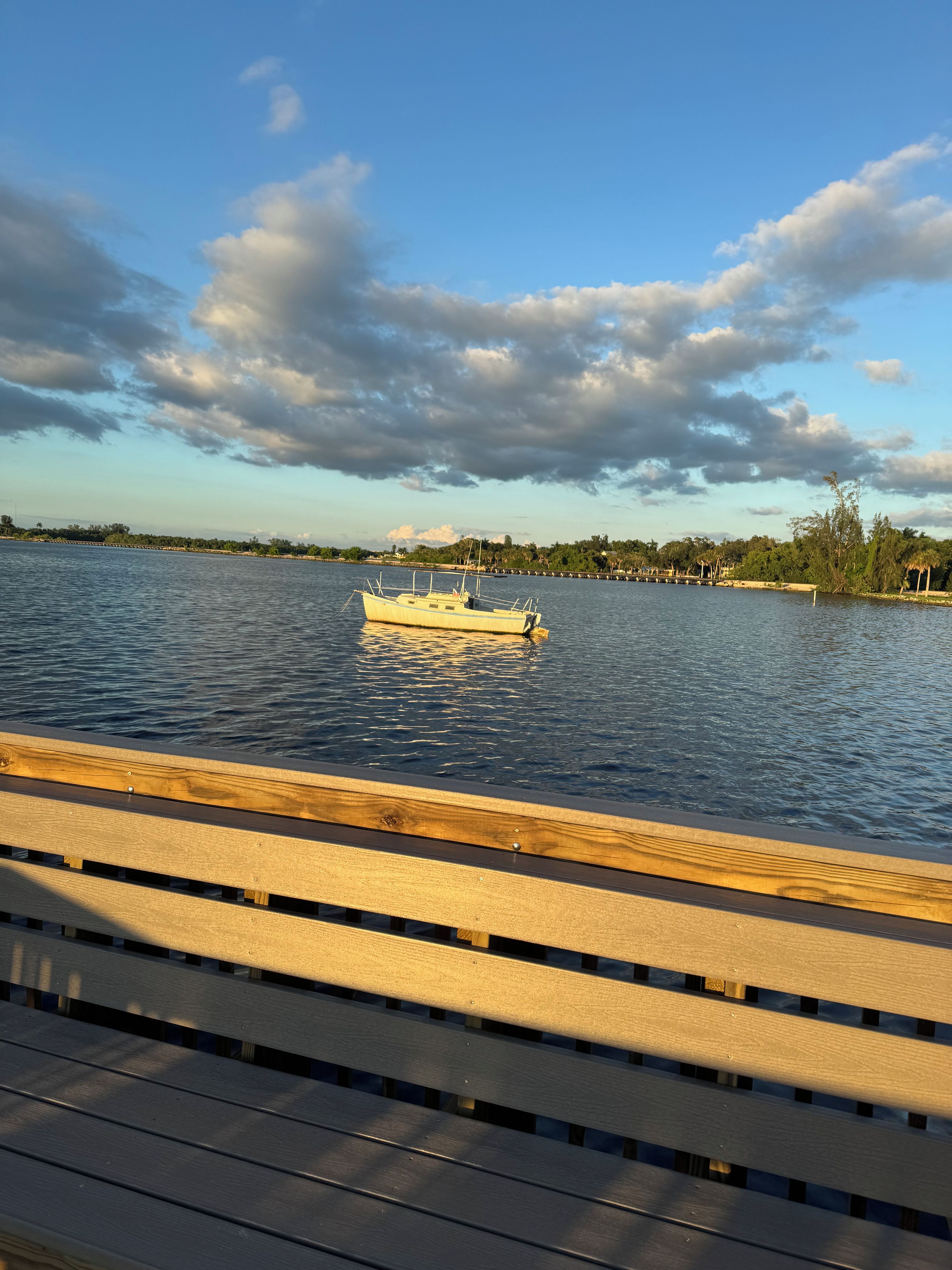 Une jetée en bois s’étendant au-dessus d’une étendue d’eau calme, avec un bateau ancré au loin.