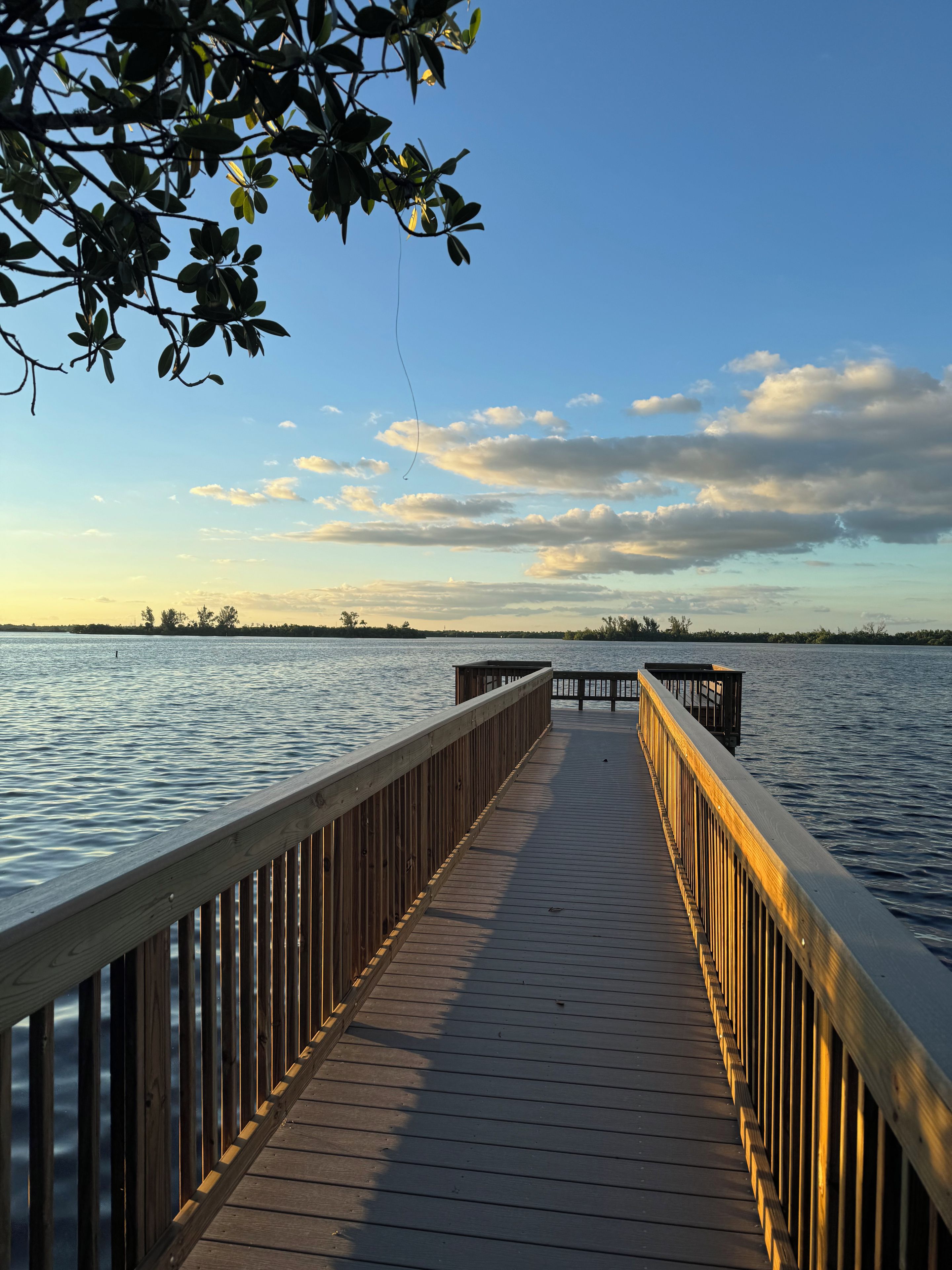 Un muelle de madera se adentra en aguas tranquilas, con un cielo despejado.