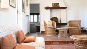 A living room with a sofa, wicker chairs, a small table, a fireplace, and a kitchen in the background. -  PP03 - Potenza Picena, wonderful villa with sea view (Potenza Picena)