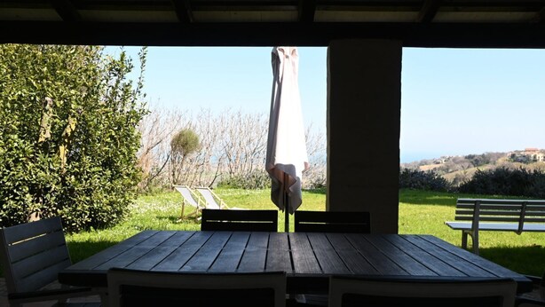 An outdoor patio with a table and chairs, a bench, and a view of a grassy area with trees and hills. -  PP03 - Potenza Picena, wonderful villa with sea view (Potenza Picena)