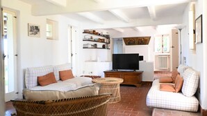 A living room with a sofa, a television, wicker furniture, and a brick floor. -  PP03 - Potenza Picena, wonderful villa with sea view (Potenza Picena)