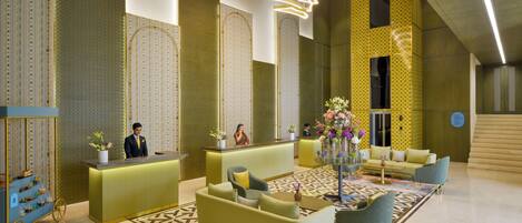 Vestíbulo de hotel con mostrador de recepción, zona de estar y detalles decorativos.