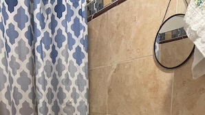 Un baño con inodoro, lavamanos, espejo y cortina de ducha.